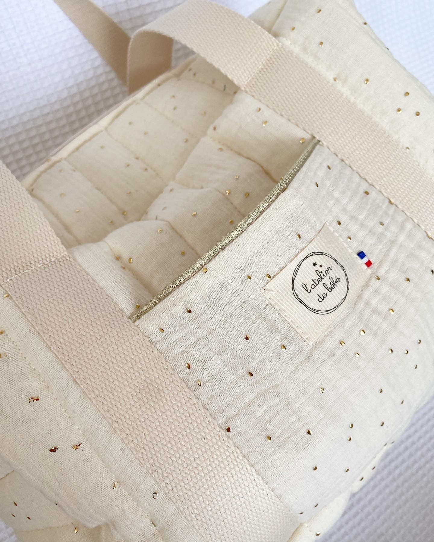 zoom sur poche plaqué du sac a langer mini , passepoil doré , sur tissu écru pois or