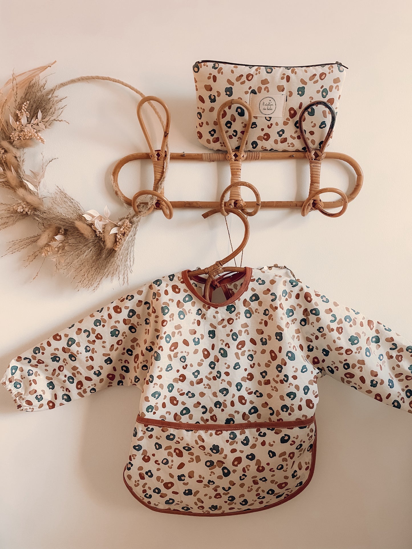 Tablier bebe / enfant en coton enduit pour atelier créatif ou diversification alimentaire . Le tablier contient une poche devant pour rattraper les aliments et une nouette au dos pour l’ajuster à la taille de bebe/ enfant .Imprimé Leopard tendance et mode .Vêtement évolutif et confortable. en accessoire sur porte manteau une petite trousse en coton enduit imprimé leopard , fermeture avec zip couleur chocolat marron , imprimé leopard .